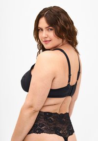 Black lace bra with ribbed texture and adjustable straps, paired with matching lace panties. Features decorative floral accents.