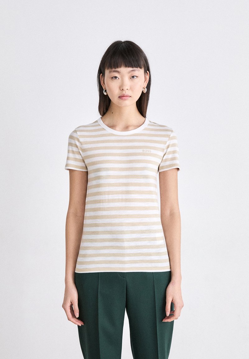 T-shirt à rayures à manches courtes en coton beige et blanc, avec un col rond et un petit logo sur la poitrine.