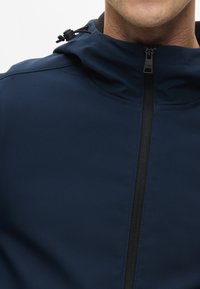 Mørkeblå zip-up hættejakke med en glat tekstur, med sort lynlås og en snorejustering i hætten.