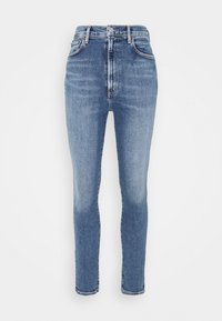 Jeans de mezclilla azul de talle alto con silueta ajustada, textura ligeramente desgastada, cinco bolsillos y cierre de botón de metal.