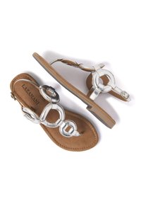 Vlakke sandalen met een bruine leren basis en zilverkleurige metallic banden met ronde accenten. Minimalistisch ontwerp met een lichtgewicht, open vorm.