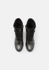 Botas de tobillo negras con un acabado brillante, que cuentan con cremalleras laterales, cordones frontales y un interior texturizado. Punta redondeada y suelas resistentes.