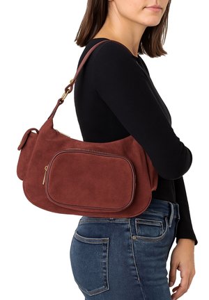 Brown suede handbag with a rounded shape, featuring a front zip pocket, a shoulder strap, and gold hardware accents.