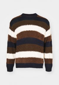 Randig tröja i brunt, marinblått och vitt med en strukturerad stickning. Har en rund hals och ribbade ärmslut. Mjuk och fluffig material.