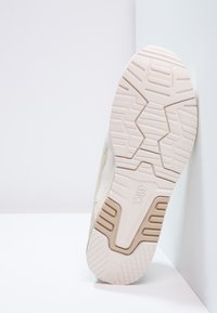 Podešev boty ve světle béžové barvě s texturovanými grip vzory a jemnými akcenty. Materiál se zdá být guma s vzorovaným designem pro lep�ší přilnavost.