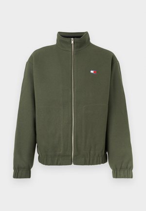 Olivengrønn zip-up jakke laget av mykt stoff, med høy krage og elastiske mansjetter, med en liten flerfarget logo på brystet.