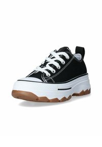Zapatilla negra de lona con cordones blancos, una suela intermedia blanca y robusta con una franja negra, y una suela exterior de goma marrón con agarre texturizado.