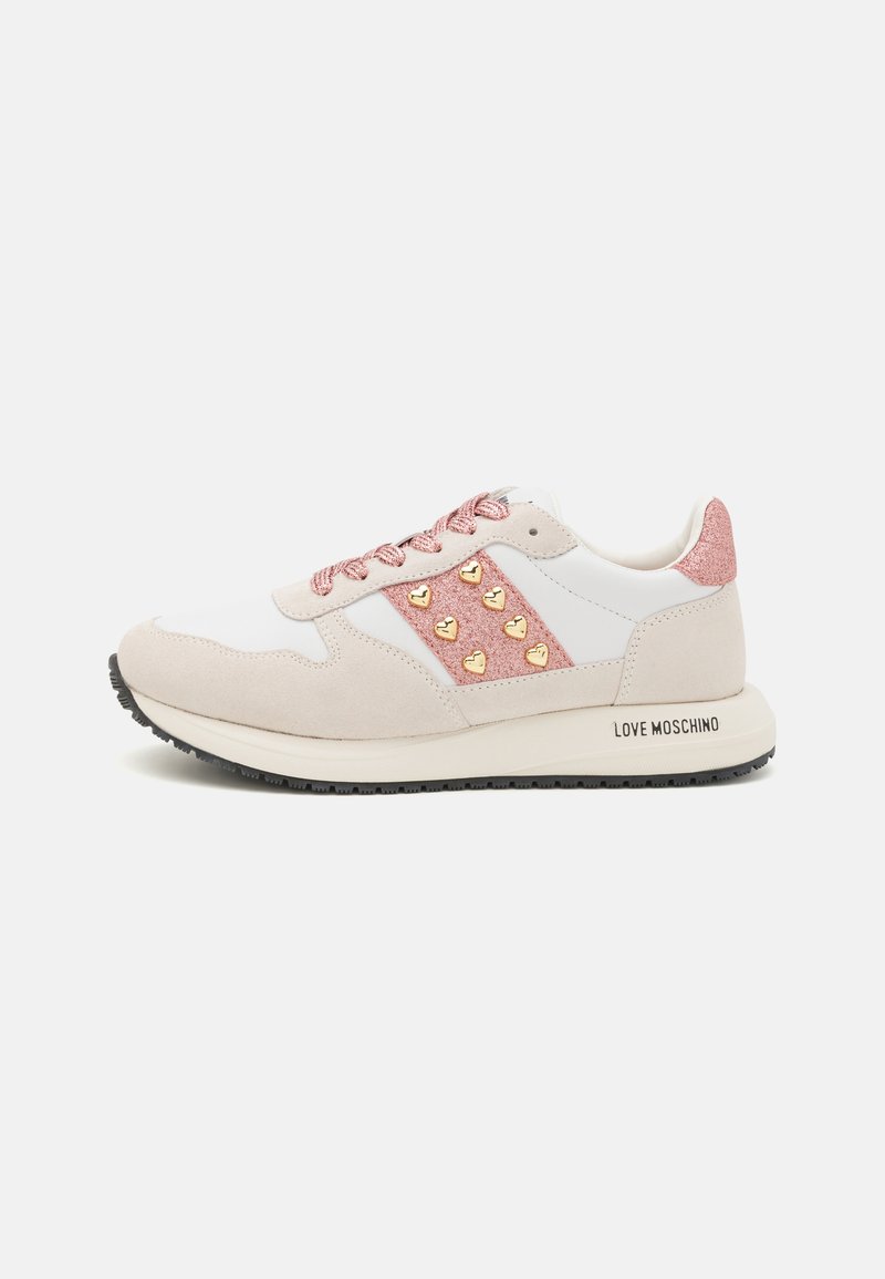 Sneakers with a white and beige design, featuring a pink glittery panel, gold heart accents, and textured laces. Black rubber sole.
