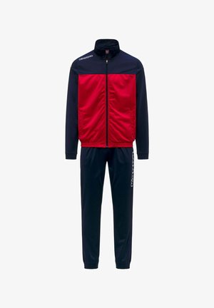 Veste de sport rouge et bleu marine zippée avec un pantalon de survêtement bleu marine assorti comportant un texte de logo blanc sur la jambe gauche.