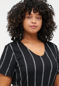 Black V-neck top with horizontal white stripes; short sleeves, textured fabric, and subtle sheen.