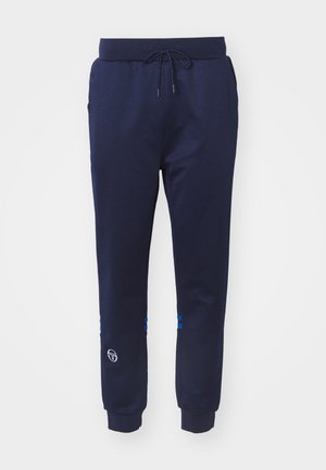 Tumedad sinised spordipüksid, mis on valmistatud siledast kangast. Neil on nööriga kummirihm ning sinised aktsenttriibud pahkluude juures, koos logo detailiga hemmi lähedal.