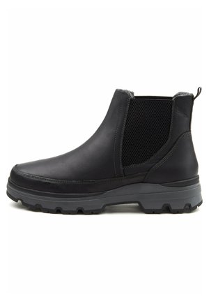 Bottette noire en cuir avec panneau latéral élastique, semelle épaisse à relief et languette à l'arrière, conçue pour la durabilité et le confort.