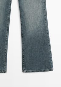 Jeans a zampa di elefante a vita alta in denim azzurro chiaro con una texture consumata, orlo pulito e dettagli di cuciture minime.