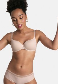 Soutien-gorge beige à armatures avec une texture lisse et un motif chevron subtil, associé à une culotte sans coutures assortie avec des accents de dentelle.