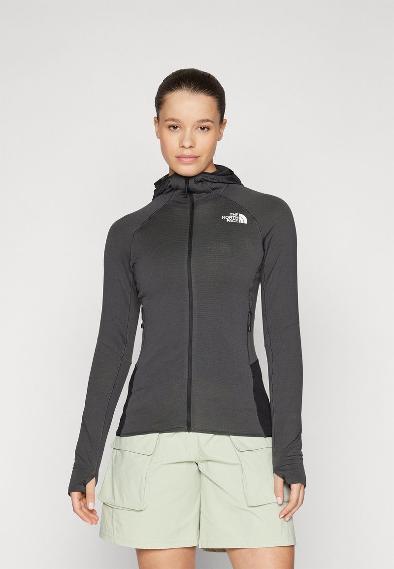 Black zip-up jacket with a hood, made from textured material. Features logo on the chest and long sleeves with thumb holes.