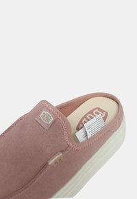 Scarpa slip-on rosa con materiale superiore morbido, suola in gomma bianca e cuciture testurizzate. Presenta una patch del logo sul lato.