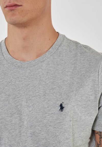 T-shirt in cotone grigio con collo tondo e maniche corte, caratterizzata da un piccolo logo ricamato blu navy nell'area del petto sinistro.