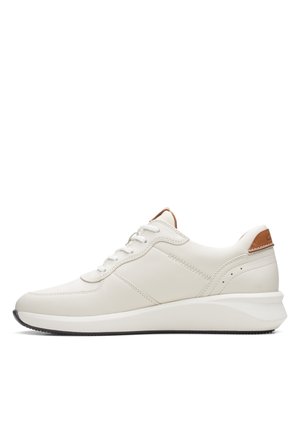 Biały skórzany sneaker z jasnobrązową pętelką na pięcie, sznurowaniem z przodu i grubą białą podeszwą z czarnym bieżnikiem, pokazany z profilu bocznego.