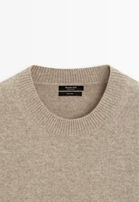 Maglione beige in lana con scollo rotondo a coste. Presenta una trama liscia e un motivo sottile. L'etichetta riporta "Massimo Dutti, 100% lana."