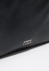 Czarna torba typu tote wykonana ze skóry o gładkiej teksturze, z wytłoczonym logo "BIMBA Y LOLA" w kolorze srebrnym oraz minimalistycznym designem bez dodatkowych ozdób.
