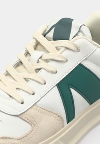 Białe sneakersy z akcentami w kolorze turkusowym, z górą z gładkiej skóry, zamszowymi detalami, płaskimi beżowymi sznurówkami oraz teksturowaną gumową podeszwą.