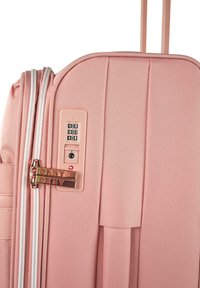 Maleta rígida en rosa claro, con textura acanalada vertical, cremalleras dobles con la marca DKNY, cerradura combinada y mango telescópico.