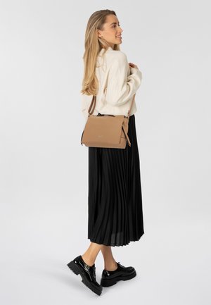 Tan leren schoudertas met een gladde textuur en ritssluiting. Zwarte geplooide rok en glanzende zwarte schoenen maken de outfit compleet.