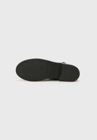 Black shoe sole with textured rubber material. Features a smooth, curved shape and embossed "MICHAEL KORS" logo.