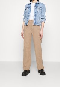 Ljusblå denimjacka med knäppning fram, kombinerad med beiga kordbyxor. Svarta klumpiga klackstövlar fulländar outfiten.