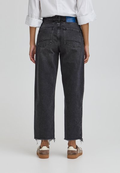 Črne jeans hlače z visokim pasom in širokimi nogavicami ter strganimi robovi. Dva zadnja žepa in modra oznaka na pasu, ki prikazuje klasičen dizajn.