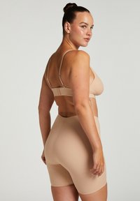 Naadloze, natuurlijke sportbeha en high-waisted shorts, gemaakt van zacht, rekbaar materiaal. Verstelbare bandjes en een gladde textuur.