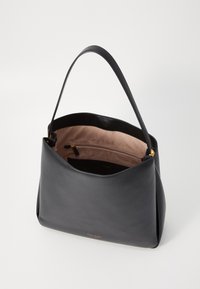 Black leather tote bag with a smooth texture, features a beige suede interior, and a gold zipper pocket. Curved design with a single handle.