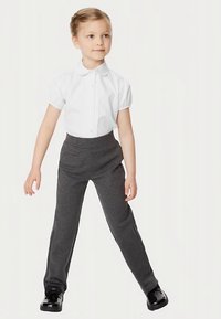 Hvid kortærmet skjorte med krave, parret med mørkegrå bukser med elastisk talje. Barnet har sorte skinnende sko på.