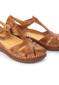 Sandalias de cuero marrón con diseño recortado, acentos cosidos y correas ajustables. Presentan una suela plana y una plantilla acolchada para mayor comodidad.