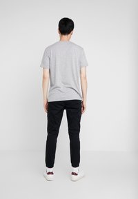 Grey short-sleeve t-shirt, paired with black cargo pants featuring side pockets. White sneakers with dark accents. Simple, clean design.
