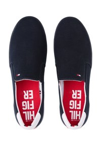 Marina canvas slip-on skor med rund tå, vita detaljer och röd innersula med vit text. Texturerad yta och flexibel sula.