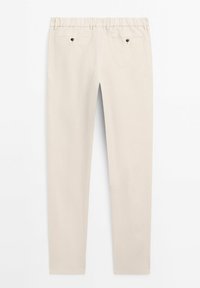 Pantalon beige sur mesure avec deux poches arrière sécurisées par des boutons noirs, passants de ceinture et coupe slim.