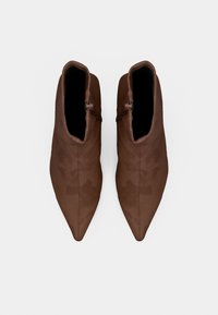 Καφέ μποτάκια μέχρι τον αστράγαλο με λεία υφή, μυτερό σχέδιο μύτης και φερμουάρ στο εξωτερικό μέρος. Εσωτερική επένδυση, μινιμαλιστικό στυλ.