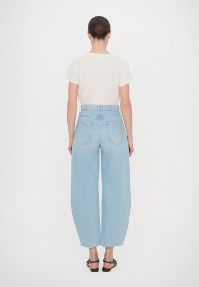 Light blue wide-leg jeans with a high waist, featuring large back pockets and a classic denim texture. Paired with a cream-colored t-shirt.