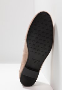 Semelle de chaussure en daim beige avec semelle en caoutchouc noir, petit talon, motif antidérapant texturé, et marquage Anna Field avec la taille 37 visible.