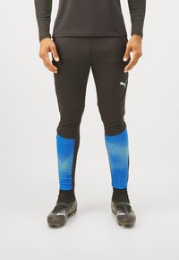Schwarze Sportleggings mit blauem Verlaufsmuster am Bund, mit einem Puma-Logo. Hergestellt aus dehnbarem, atmungsaktivem Material.
