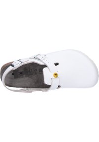 White clogs with adjustable silver metal buckles, soft leather upper, contoured insole, and a textured rubber outsole.  Flat design.