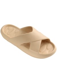 Crossband slide sandal in light beige. Made from smooth material, features a contoured footbed with textured pattern for grip.