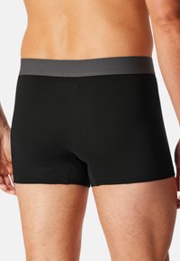 Boxer briefs neri con un elastico grigio in vita, texture liscia, design a gamba corta e dettagli di cuciture a contrasto.