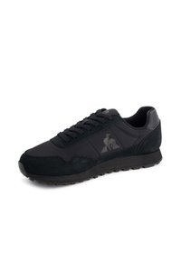 Black sneaker featuring a mix of smooth and suede textures, rounded toe, lace-up closure, and a subtle logo on the side.