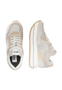 Sneaker da donna beige e bianche con tessuto testurizzato, dettagli in camoscio, suola bianca spessa e battistrada in gomma beige, mostrate da una vista dall'alto e laterale.