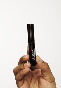 Czarna cylindryczna tuba maskary trzymana w dłoni, oznaczona jako "INGLOT Brow Shaping Mascara", o błyszczącej powierzchni i białym napisie.