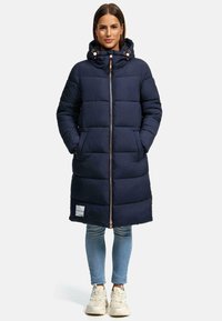 Navy blue puffer coat with a zip closure, hood, and ribbed cuffs. Features side pockets and a logo patch near the hem. Soft, quilted texture.