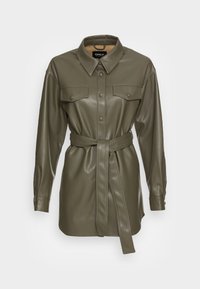 Abito camicia a maniche lunghe in eco-pelle verde oliva, con tasche a soffietto sul petto, bottoni a pressione e una cintura coordinata annodata in vita.