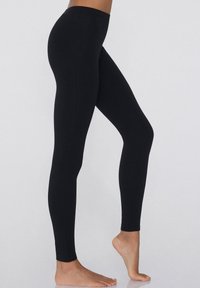 Leggings noirs en tissu extensible, avec une texture lisse, un design ajusté et une taille haute pour le confort.